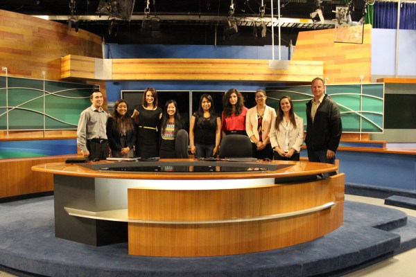 Kaci Aitchison, David Domke, and students behind the anchors' desk at Q13 FOX studio. 